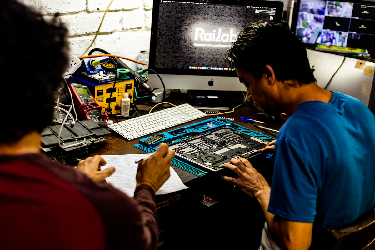 Two technicians diagnosing a TV mainboard on the workbench